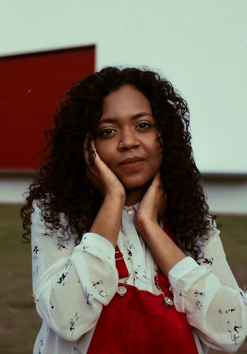 Close-Up Photo of a Woman in a White Top Posing with Her Hands on Her Face