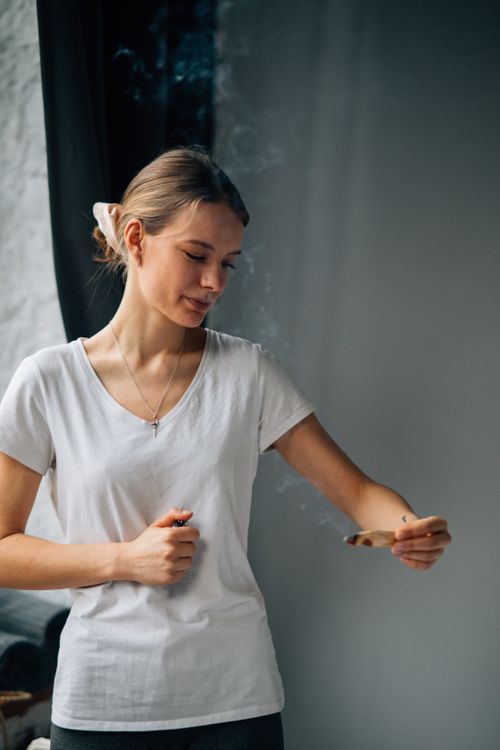 Free A serene woman holds burning palo santo, creating a calming atmosphere indoors. Stock Photo