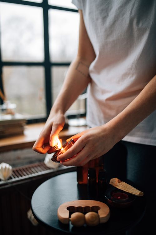 Free Hands lighting a candle by a window, creating a warm atmosphere. Stock Photo