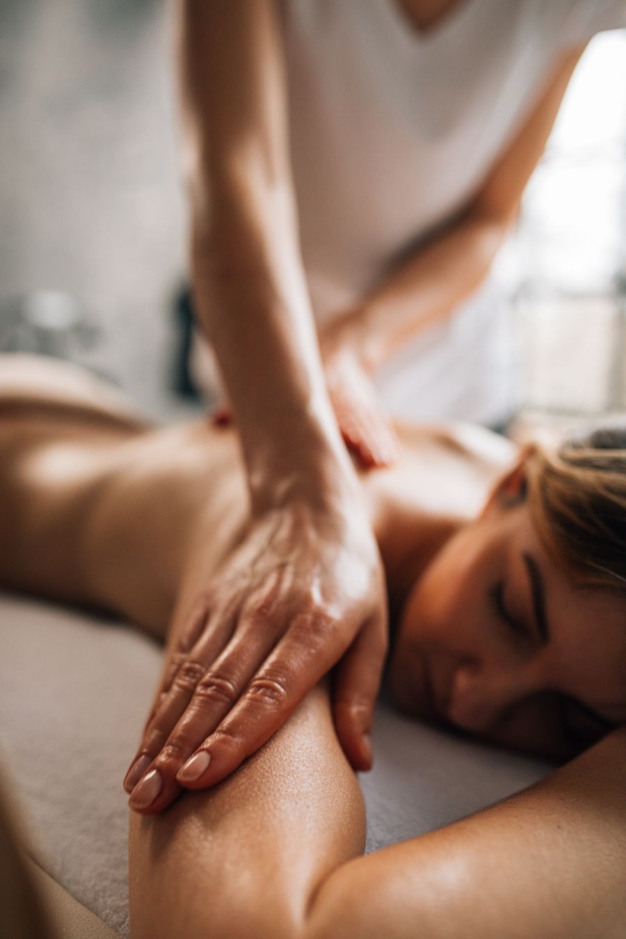 Female massage therapist providing a professional wellness massage to a male client