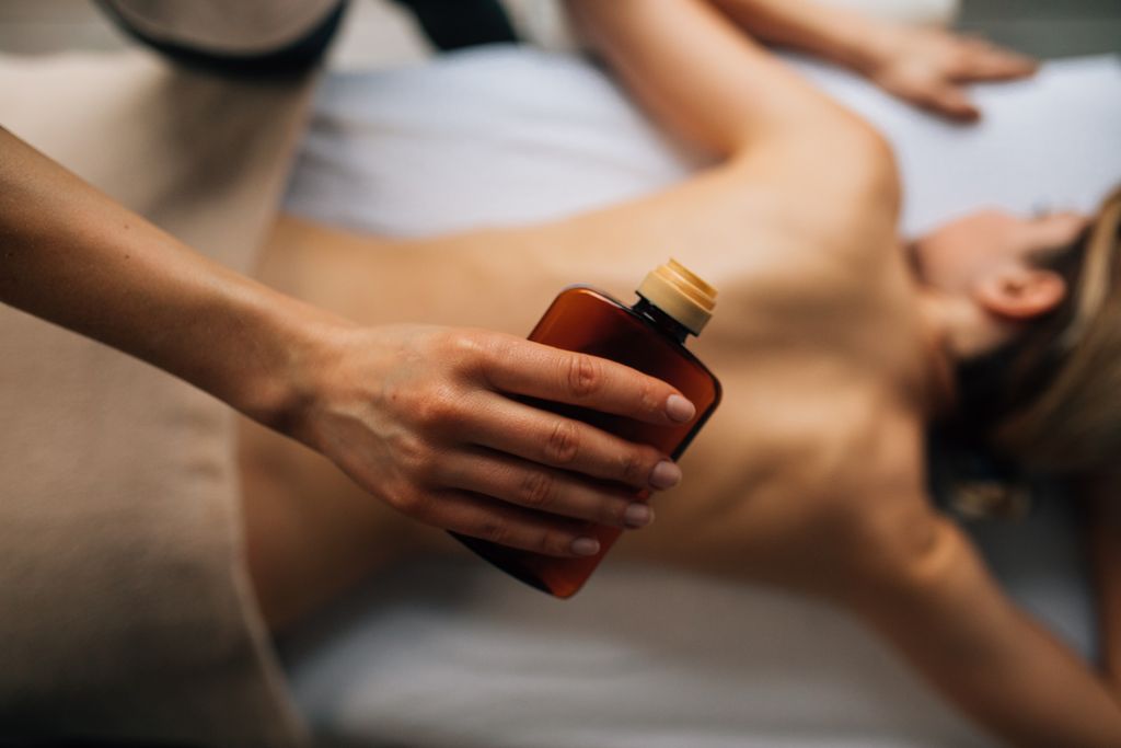 Therapist warming botanical oil for a massage