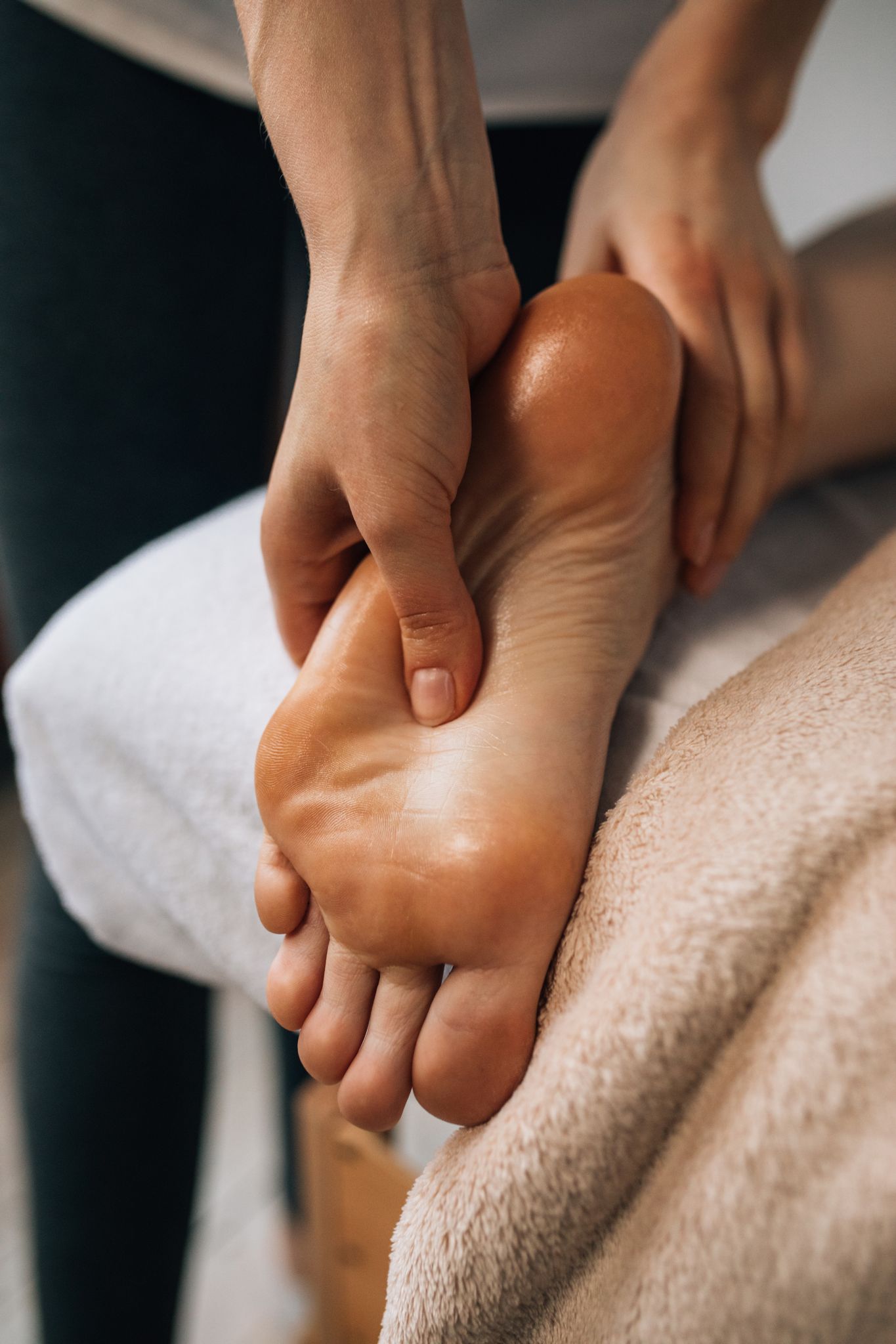 A massage therapist applying focused pressure during a foot reflexology session