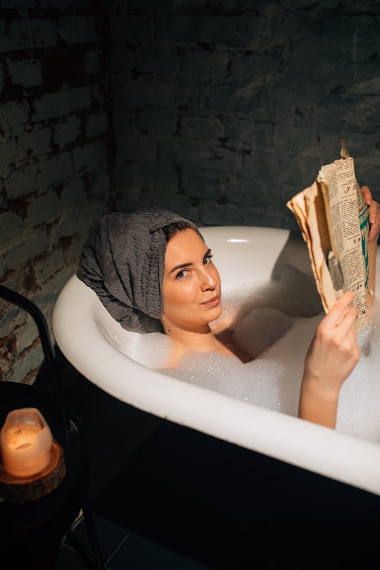 Woman Reading In Bathtub Covered With Bubbles