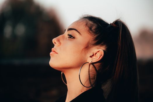 Elegant side profile of a young woman wearing hoop earrings outdoors in Mantova, Italy.