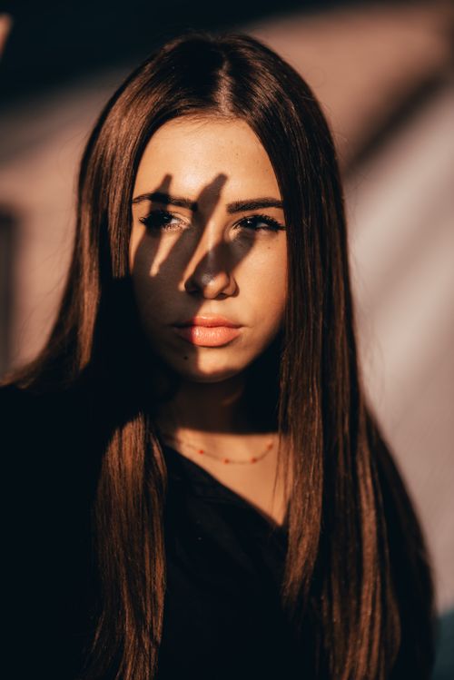 Free Artistic portrait of a woman with long hair, showcasing light and shadow play in a dramatic setting. Stock Photo