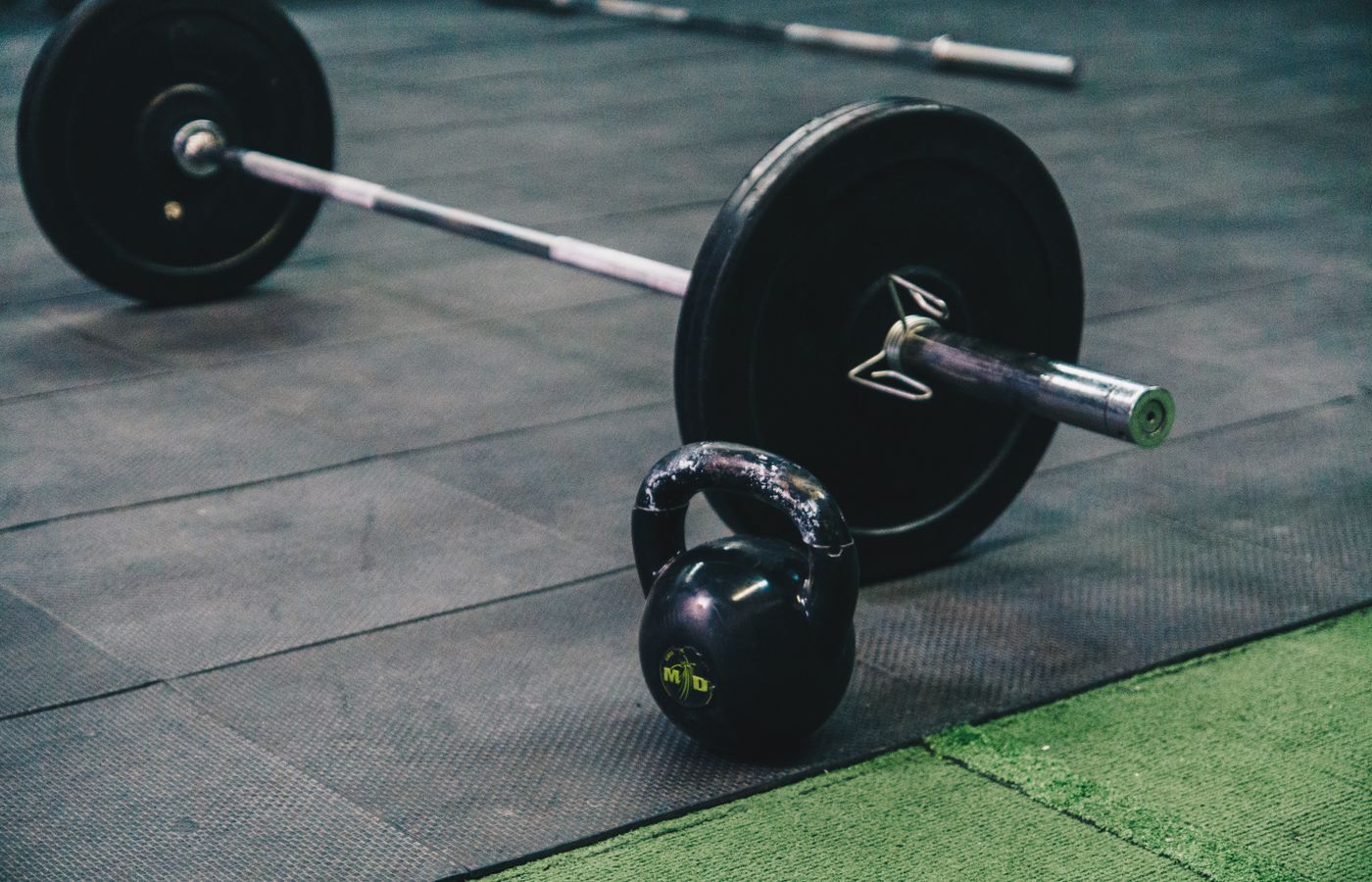 Barbell and kettlebell on gym floor, ideal for fitness and strength training themes.