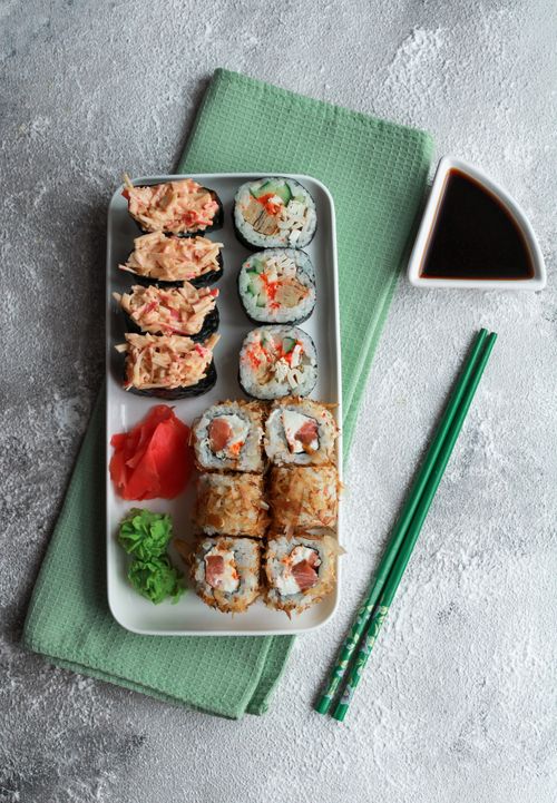 Free Delicious assorted sushi rolls served with soy sauce and chopsticks on a textured background. Stock Photo