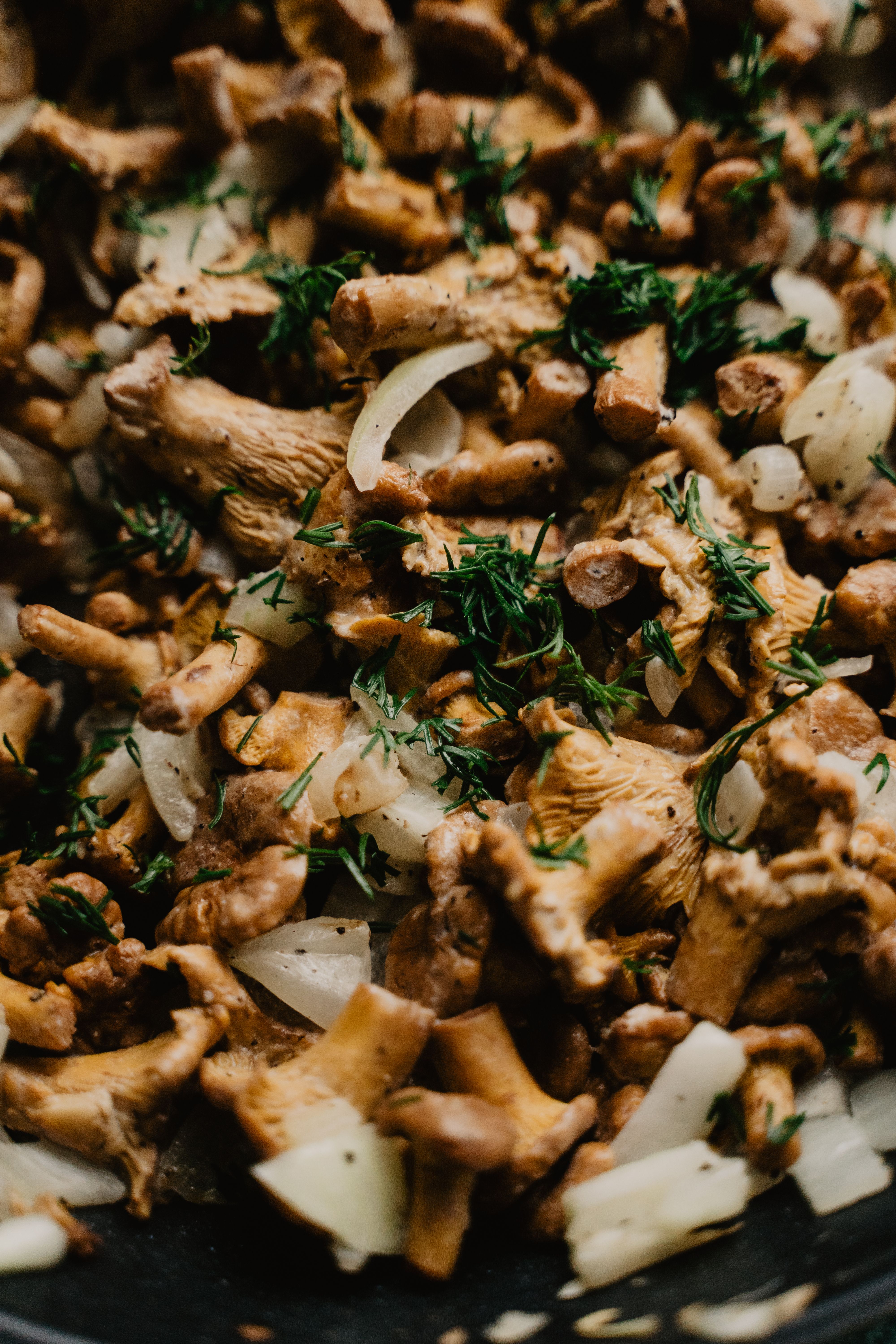 A detailed view of sautéed chanterelle mushrooms with onions and herbs, showcasing a delicious vegan dish.