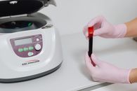 Person Holding Red Pen and White and Gray Digital Device