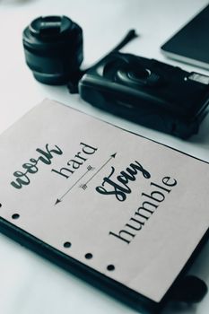 From above of diary with motivating phrase placed near camera on white table on blurred background