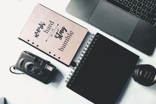 Composition of laptop with photo camera and notepads on desktop