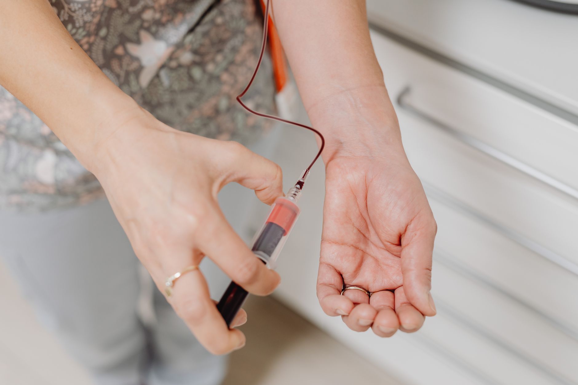 A close-up view of a blood draw procedure with syringe and vial, focusing on healthcare treatment.
