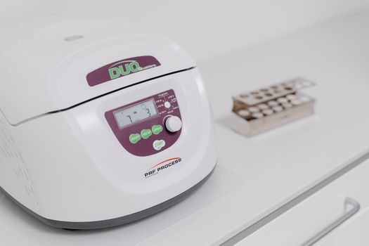 Close-up of a modern laboratory centrifuge on a sterile white surface, used in medical testing. — photo by www.kaboompics.com