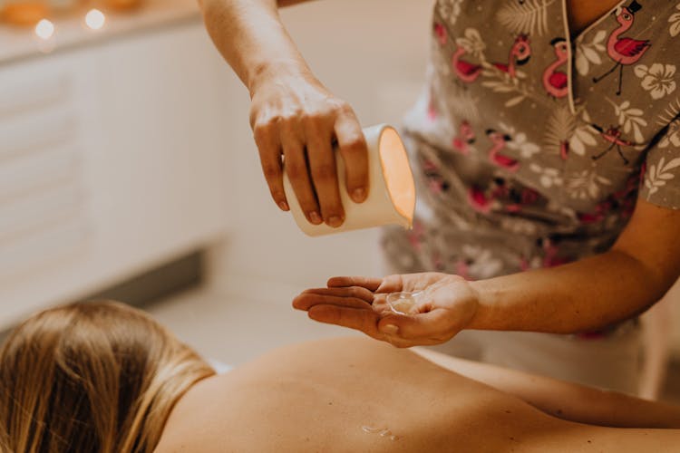 A Masseuse Pouring Oil On Her Hand