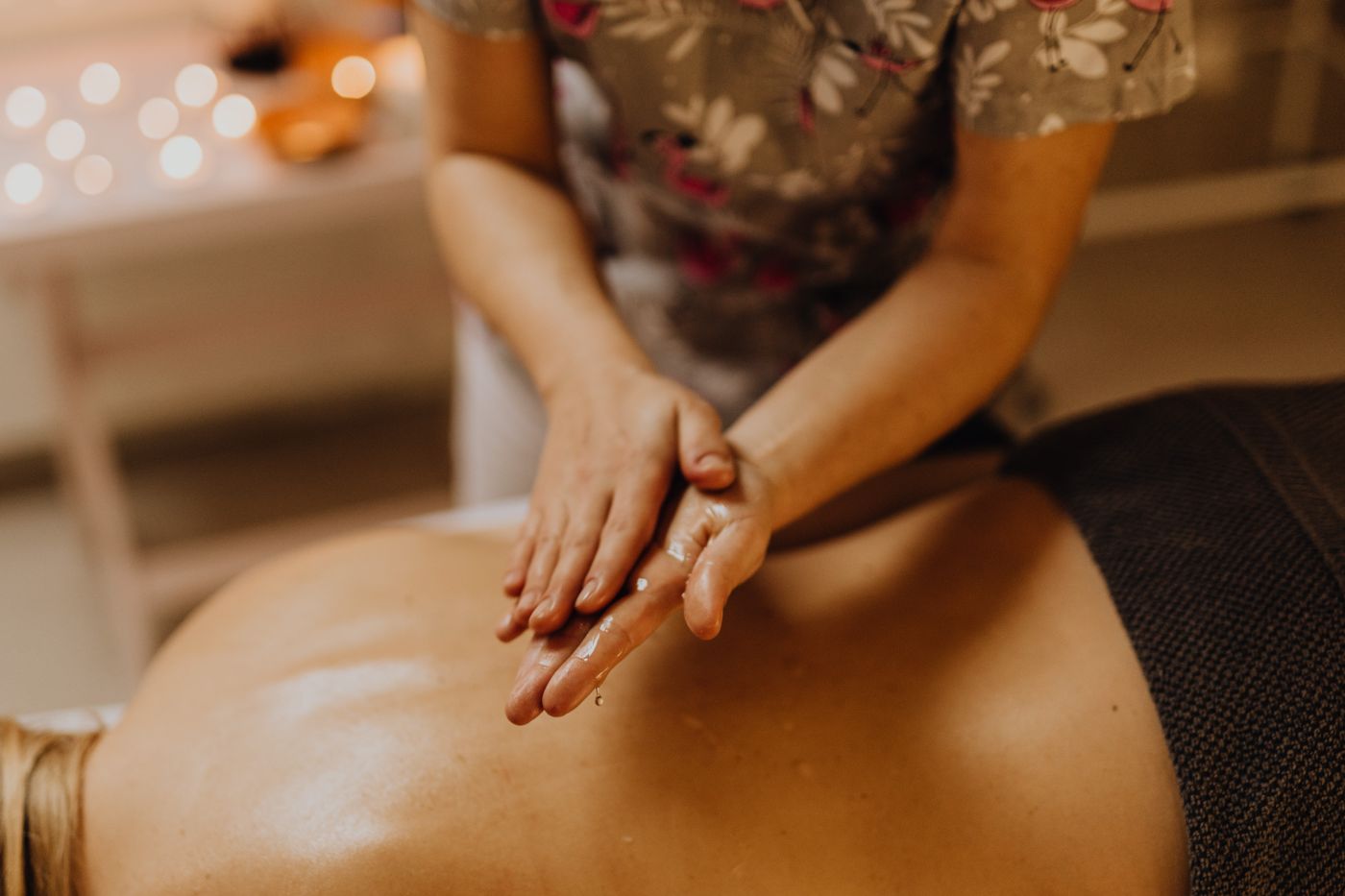 Therapist applying massage oil to a client's back in a calm treatment room