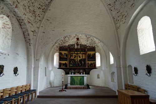 Free Interior of a medieval church with stone arches, altar, and religious artwork. Stock Photo