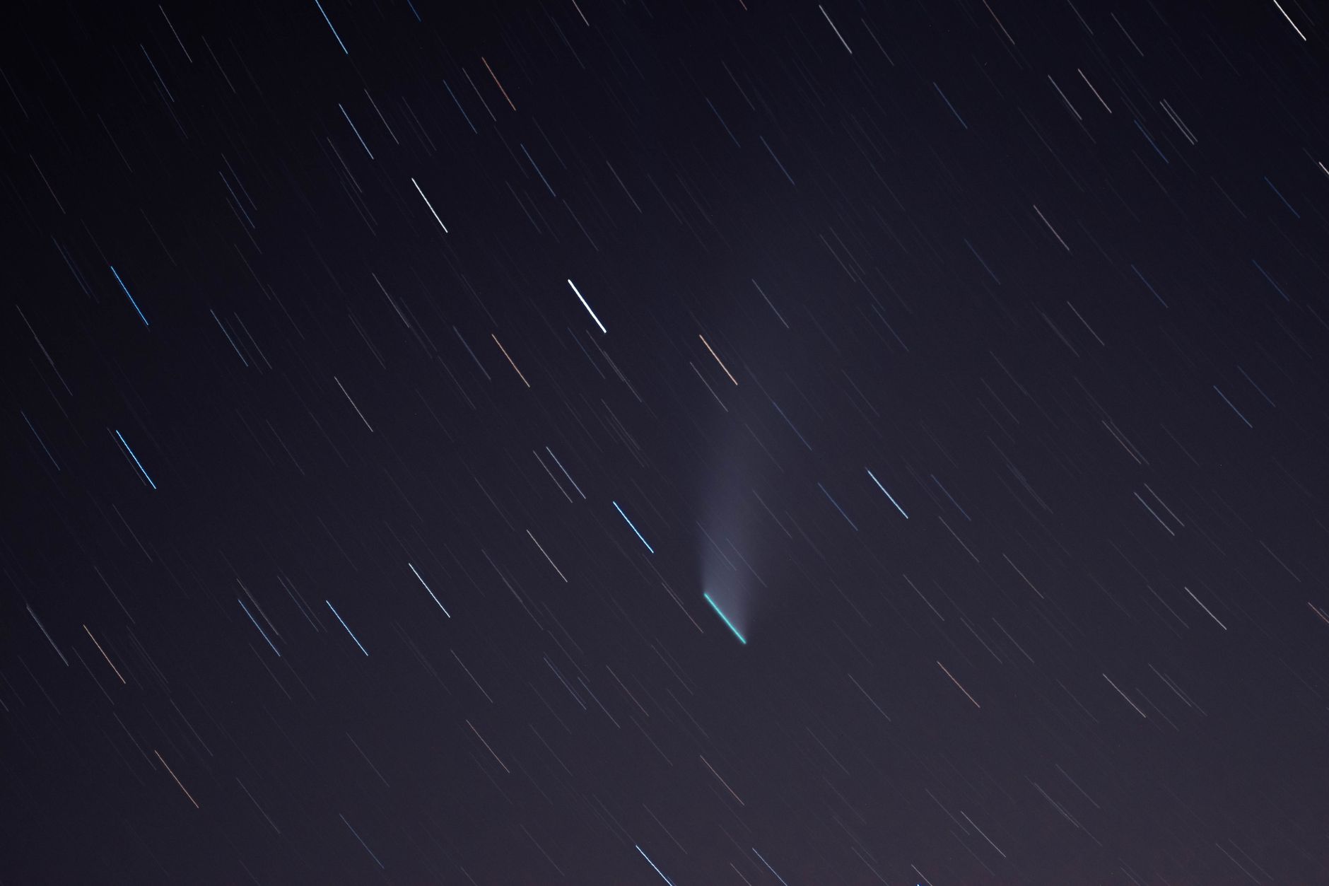 Long exposure of star trails and a comet illuminating the night sky over Airolo, Switzerland.