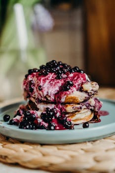 Mouthwatering stack of pancakes topped with blueberries and yogurt syrup on a plate.