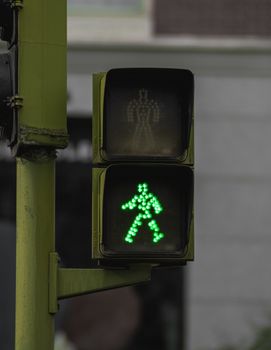 Close-up of a green pedestrian traffic sign in Madrid, ensuring crossing safety.