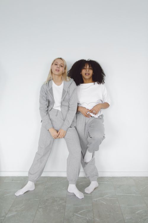 Free Two women in cozy loungewear posing indoors against a neutral background. Stock Photo