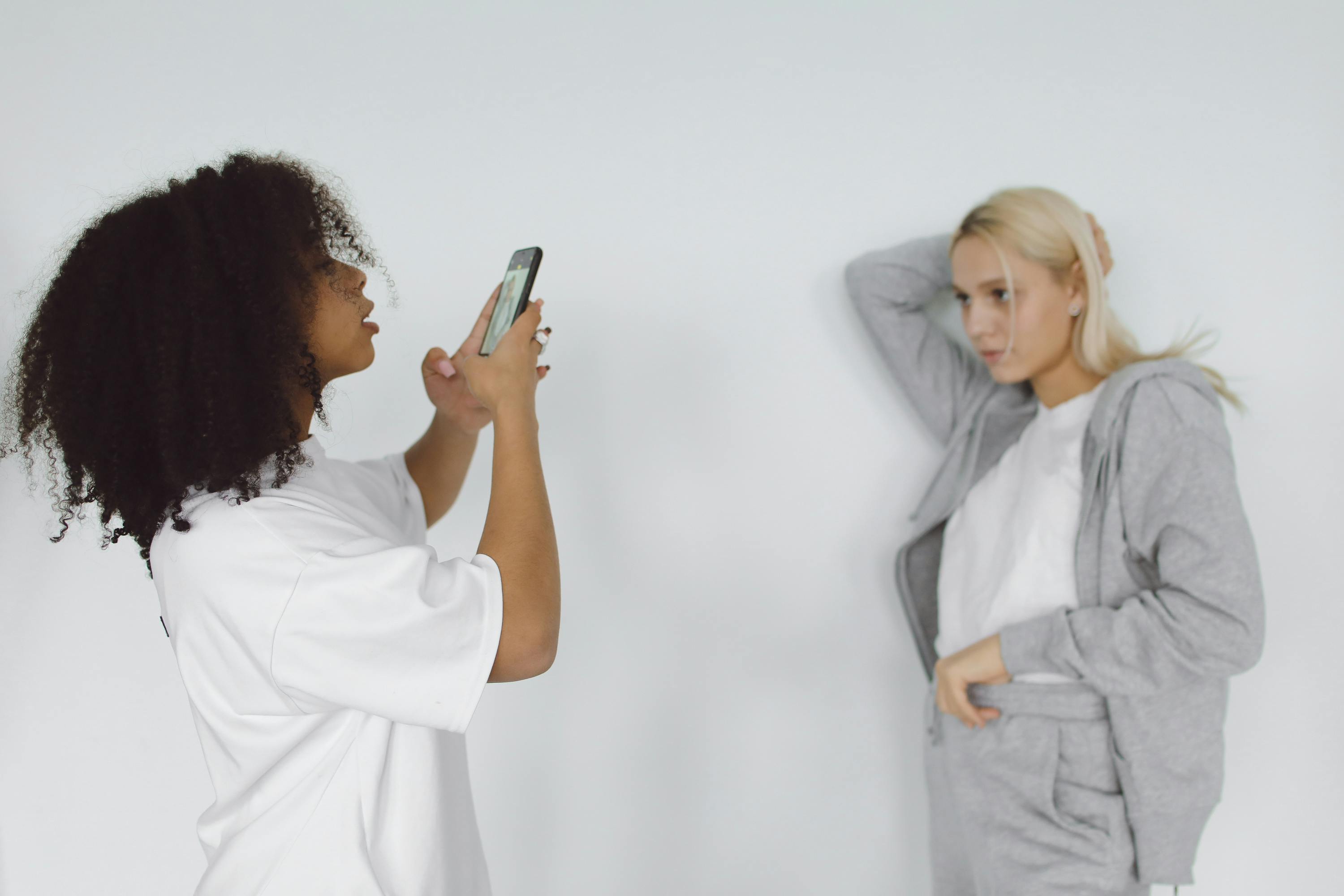 Two women capturing moments in a casual studio setting.