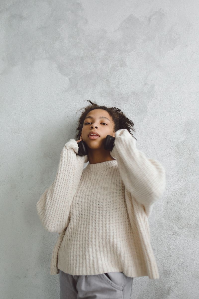 Woman in a white knit sweater wearing headphones