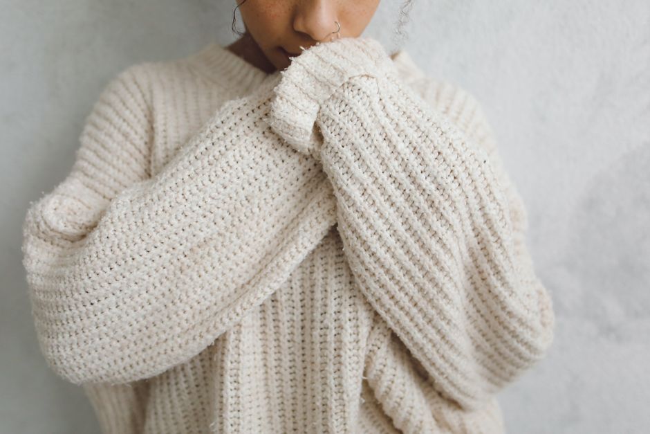 Close-up of a person in a cozy knitted sweater with a nose ring.