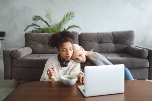 Free Friends relaxing on the couch with a laptop, enjoying a cozy and relaxed indoor setting. Stock Photo