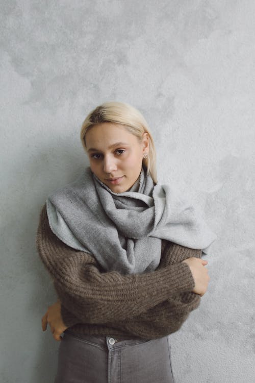 Woman in Brown Sweater Leaning on a Marble Wall