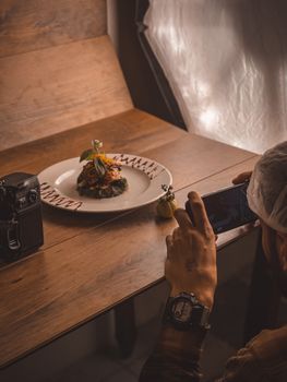 Photographer capturing a gourmet dish with an iPhone, showcasing food photography.