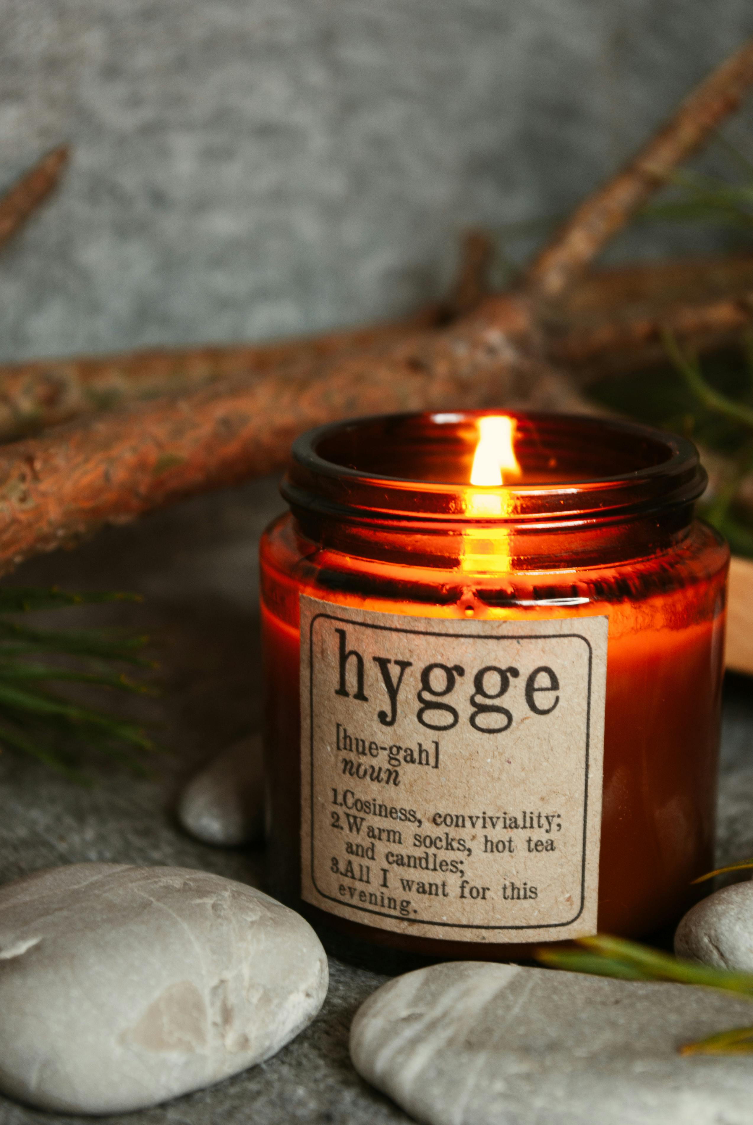 burning aromatic candle with stone and tree branches on table