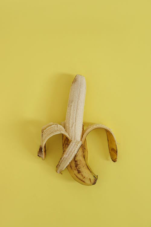 Free 
A Peeled Banana on a Yellow Surface Stock Photo