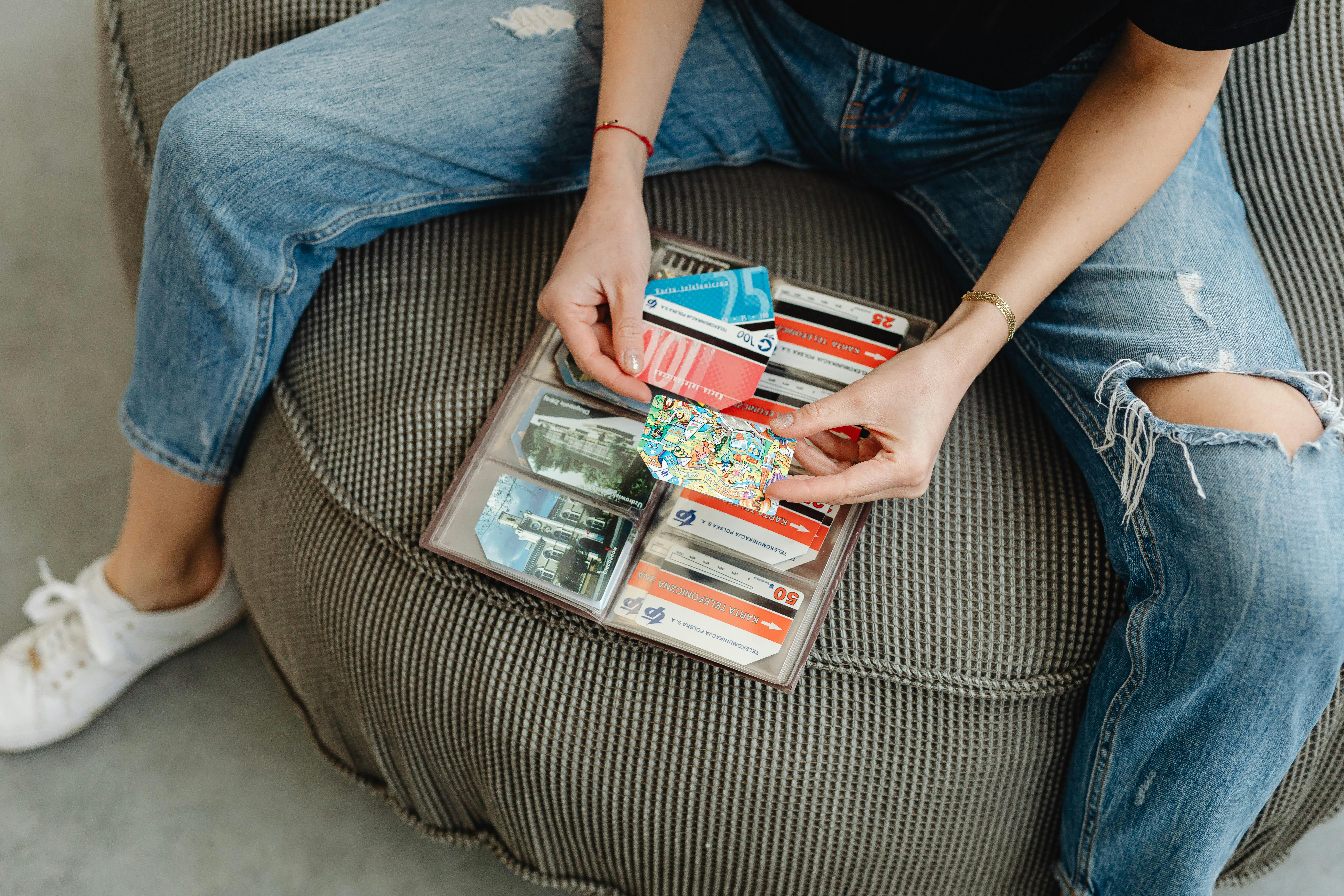 Female sitting casually organizing various colorful cards in a wallet.