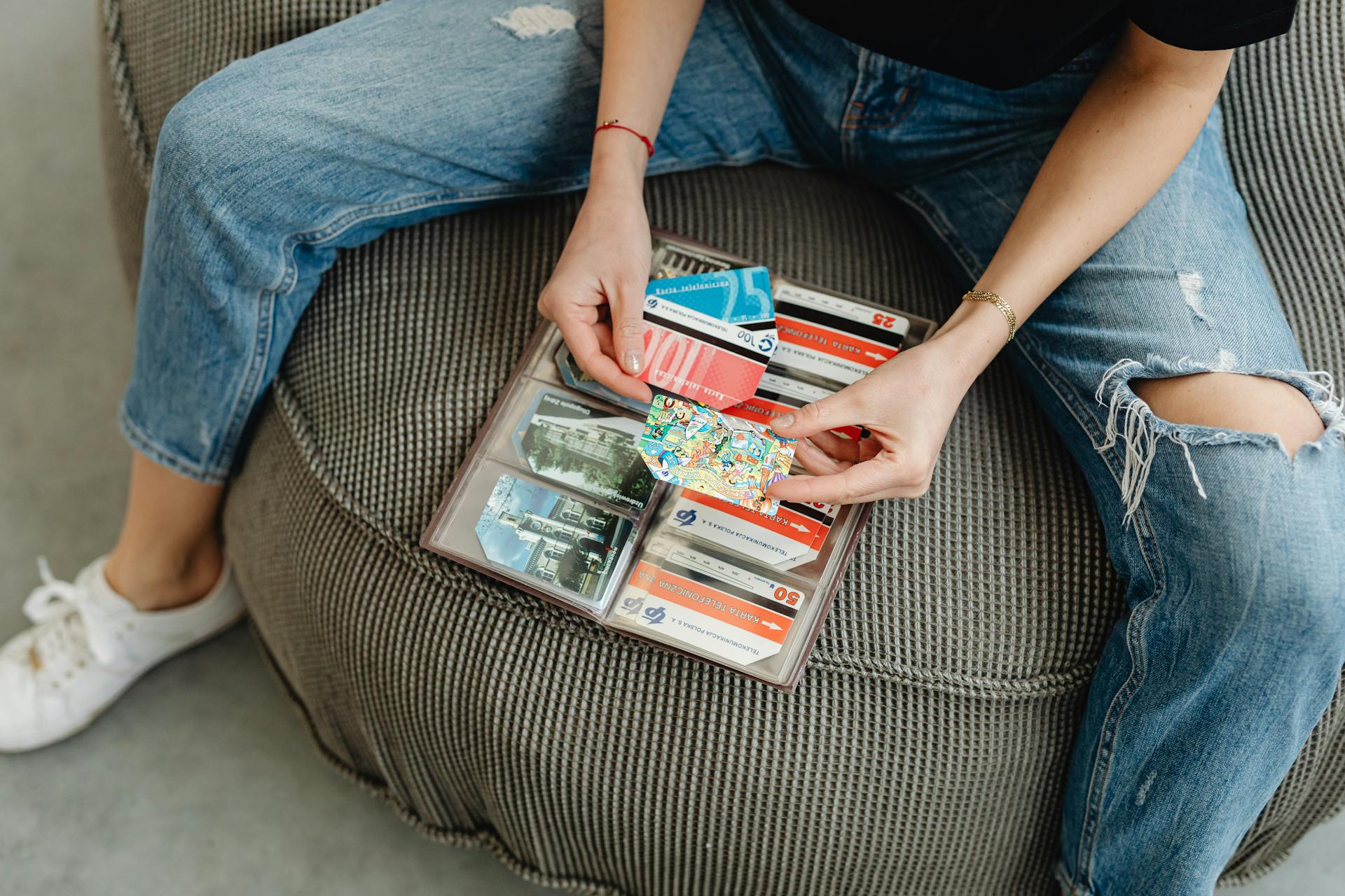 Female sitting casually organizing various colorful cards in a wallet.