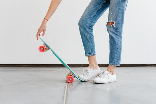 Free Person in denim jeans and sneakers with skateboard, relaxed indoor setting. Stock Photo