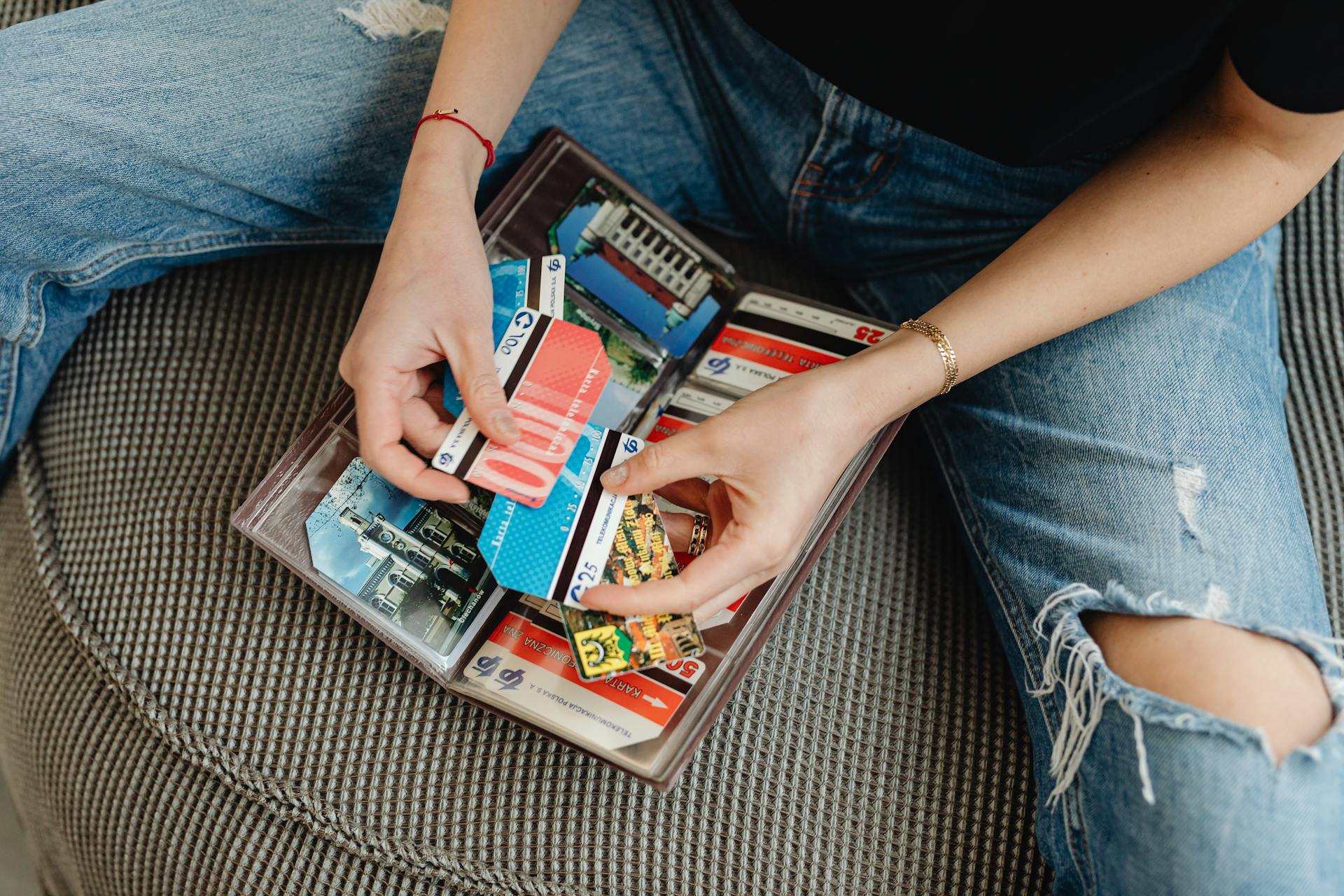 Close-up of hands sorting a collection of various vintage phone cards in a binder.