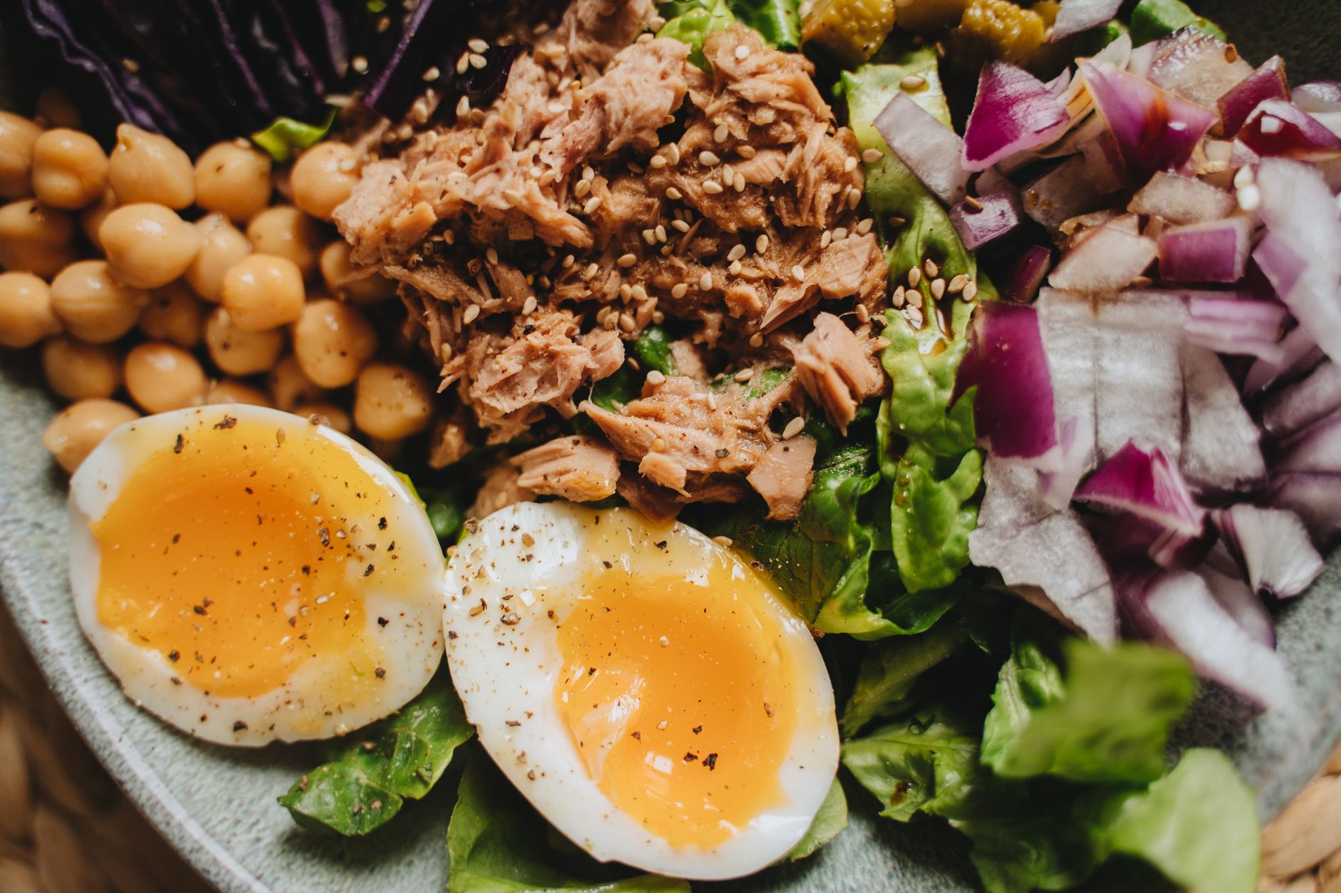 Close-up of a nutritious salad with tuna, soft-boiled eggs, and fresh vegetables.