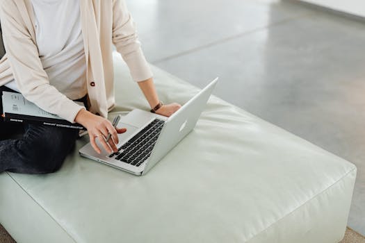 Person working remotely on a laptop with a pen, symbolizing online productivity.