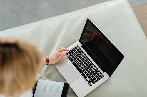 Woman Sitting On A White Leather Couch Using Laptop