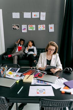 Young professionals collaborating in a modern office, surrounded by graphics and tech devices.