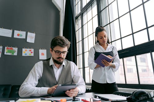 Man and Woman with Serious Face Expressions in Office with a Large Window