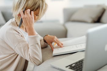 Free Woman Reading Book and Using Laptop Stock Photo