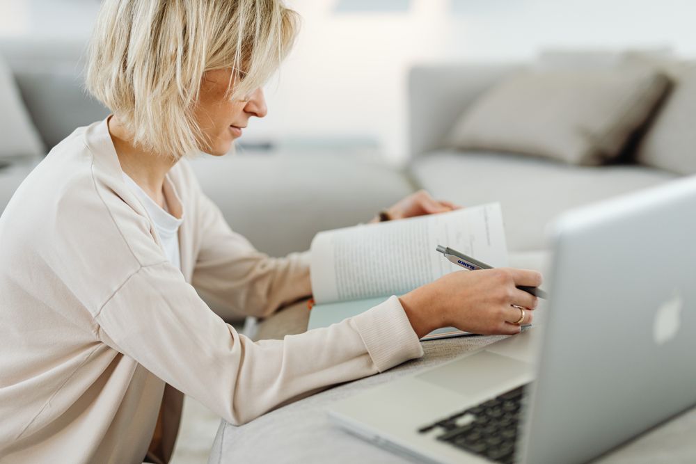 Creator taking notes beside a laptop at a home workspace, photo by Kaboompics on Pexels