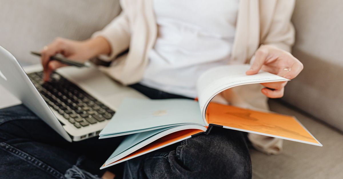 A reader with a book and an open laptop