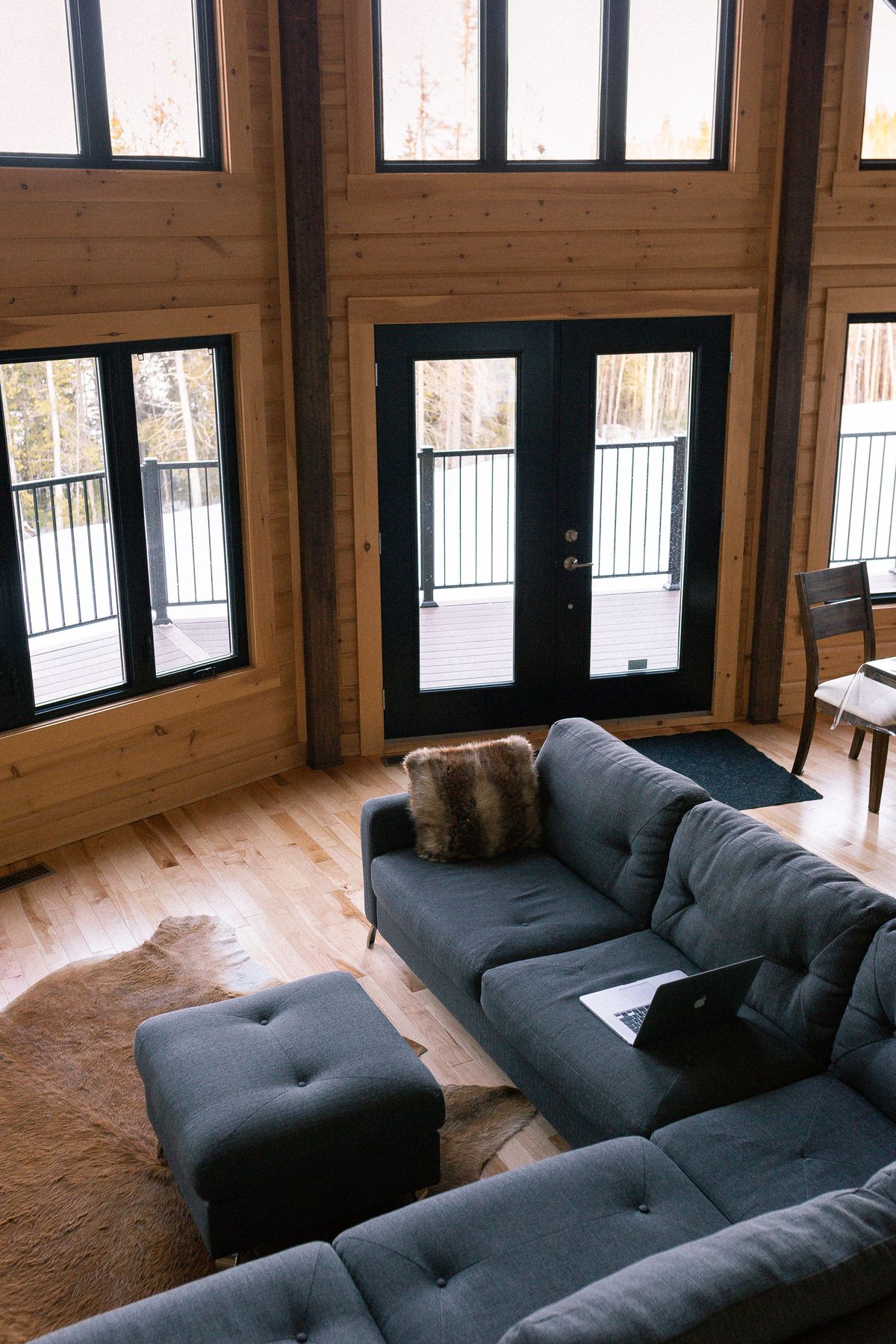 Modern cabin interior with tall timber framing and floor-to-ceiling windows allowing natural light