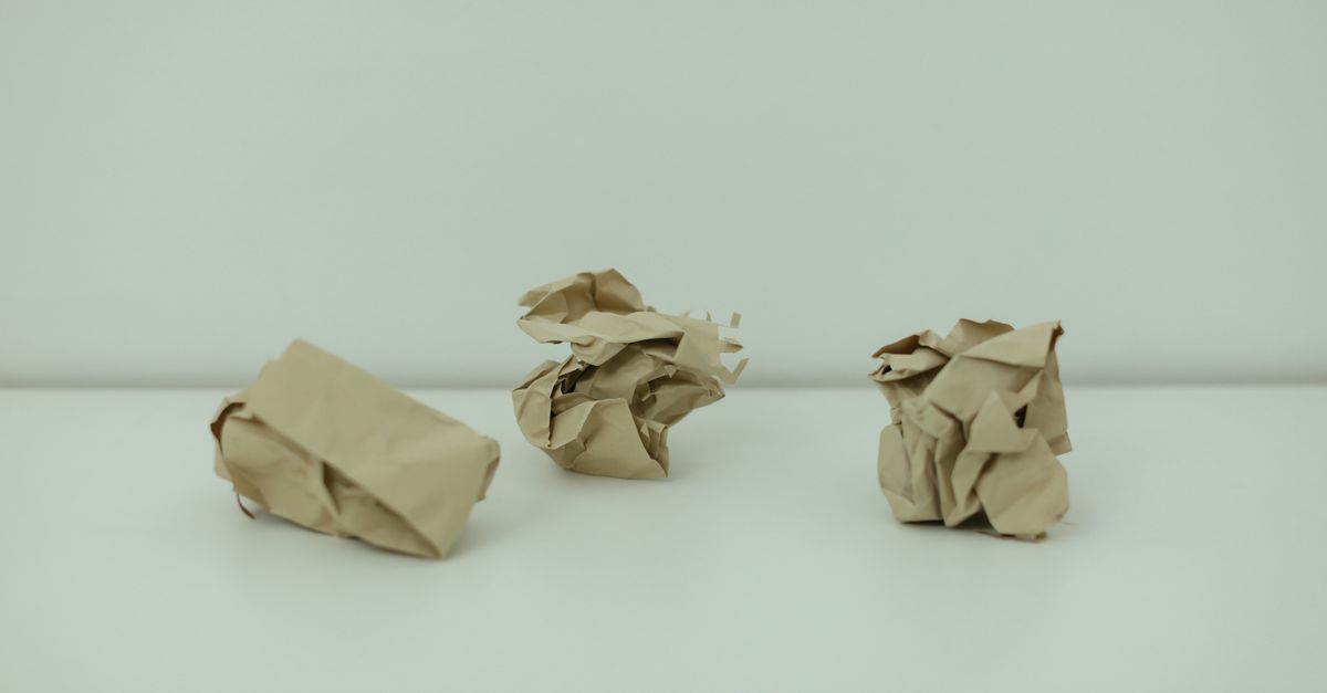Minimalist image of three crumpled paper balls on a white surface, symbolizing burnout.