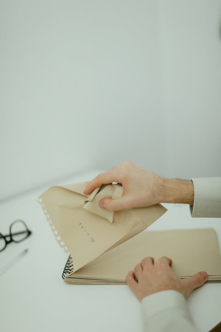 
A Person Ripping And Crumpling A Paper