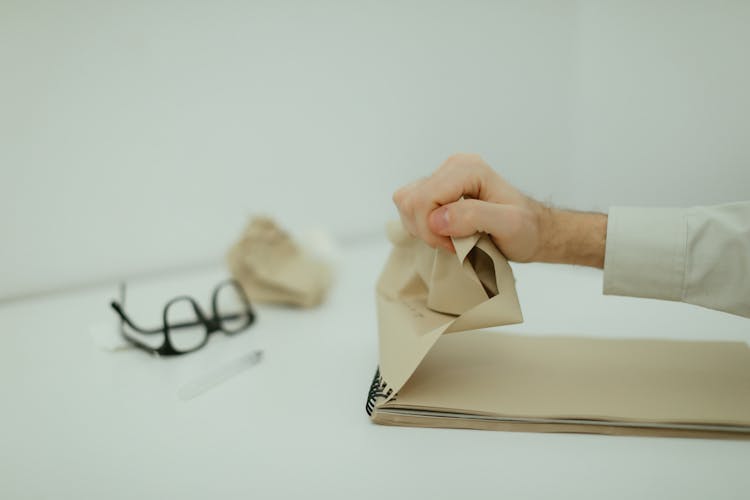 A Person Ripping And Crumpling A Paper