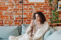 Woman in White and Brown Floral Dress Sitting on Blue Couch