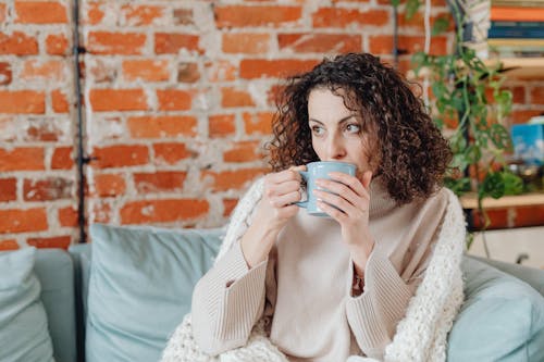 Free Woman with Curly Hair Drinking from a Mug Stock Photo